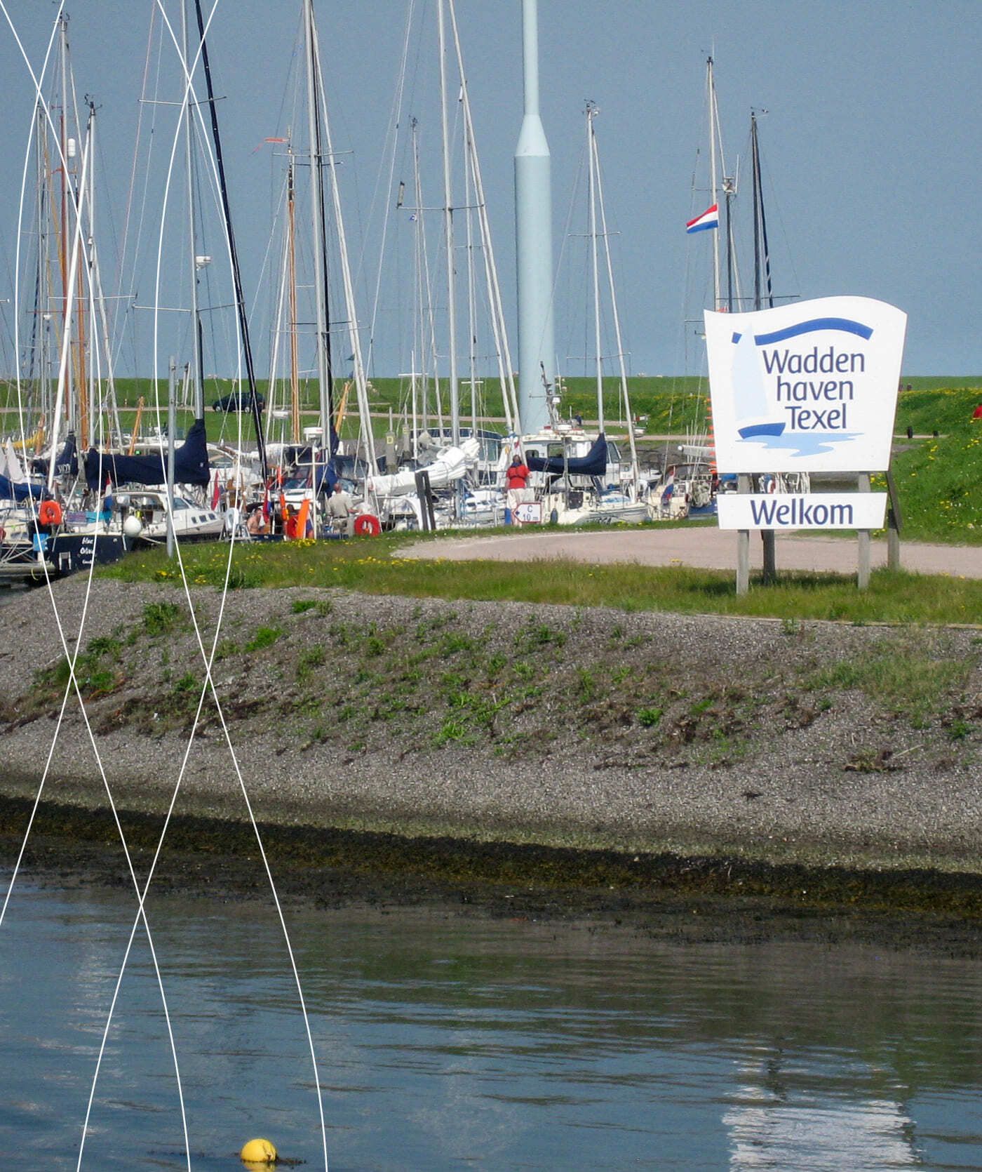 Jachthaven met talrijke aangemeerde zeilboten, een grasdijk en aan het water een bord met de tekst Waddenhaven Texel Welkom. Hier vindt u informatie over lokale webwinkels en online diensten voor bezoekers.